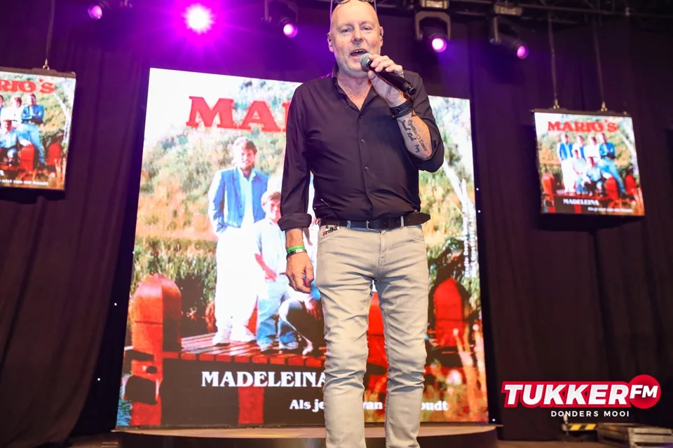 René zingt op het podium van Tukker FM, onder paarse verlichting